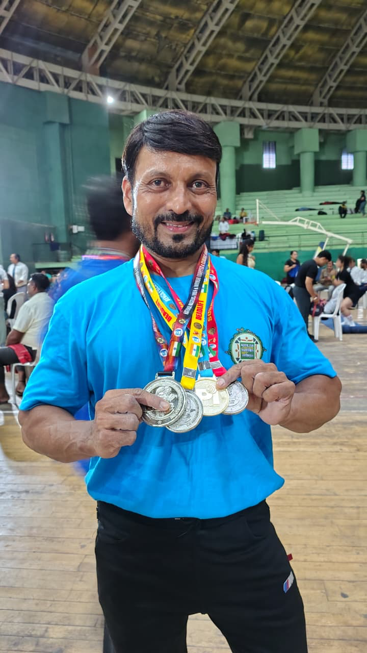 Coach Rajesh holding multiple championship medals at competition venue