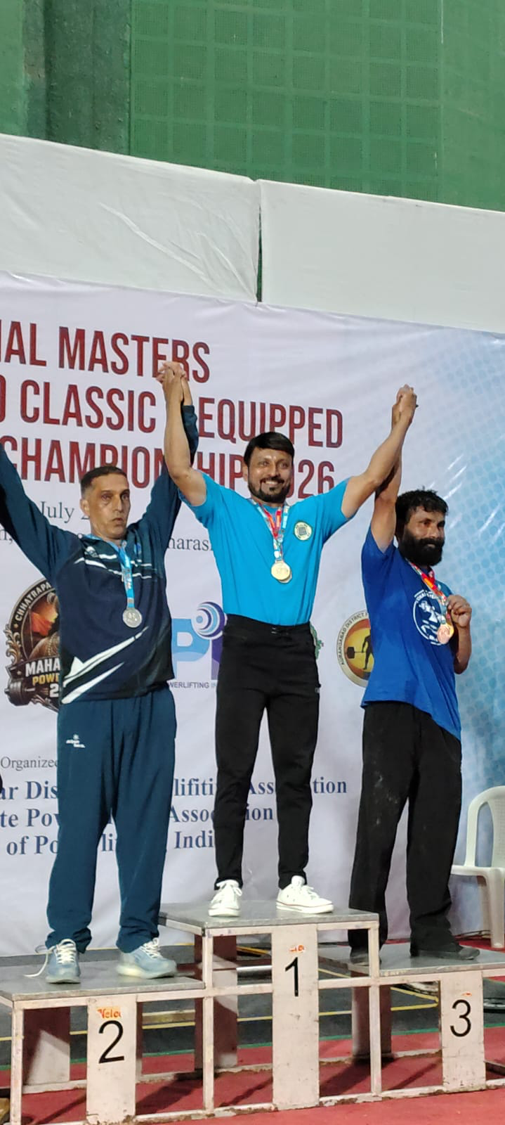 Coach Rajesh standing on 1st place podium at National Masters Powerlifting Championship 2026